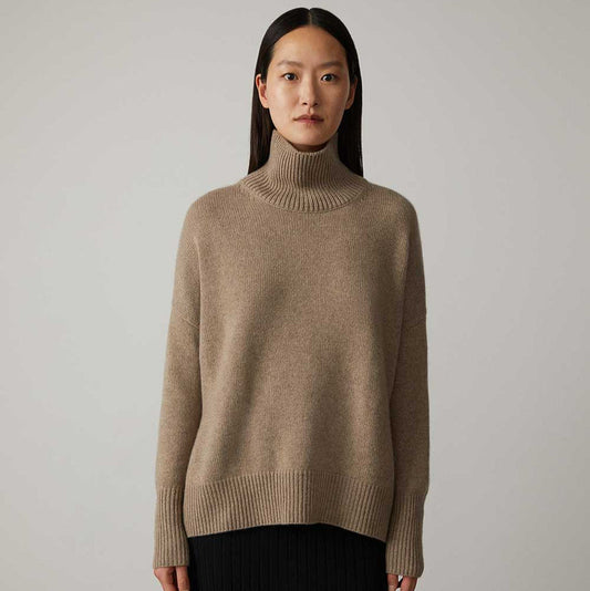 Donna con maglione a collo alto beige, stile minimalista, sfondo neutro. Moda autunnale, abbigliamento casual elegante, tendenze 2023.