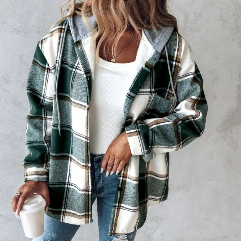 Donna con camicia a quadri verde e bianca, top bianco e jeans, tiene una tazza di caffè. Moda casual autunnale, stile urbano femminile.