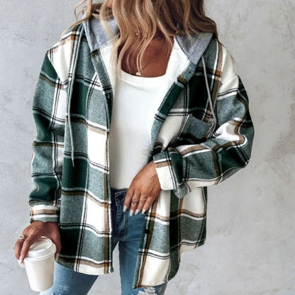 Donna con camicia a quadri verde e bianca, top bianco e jeans, tiene una tazza di caffè. Moda casual autunnale, stile urbano femminile.