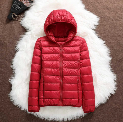 Giacca invernale rossa con cappuccio, imbottita e trapuntata, su sfondo di pelliccia bianca. Moda donna, abbigliamento caldo, stile casual.