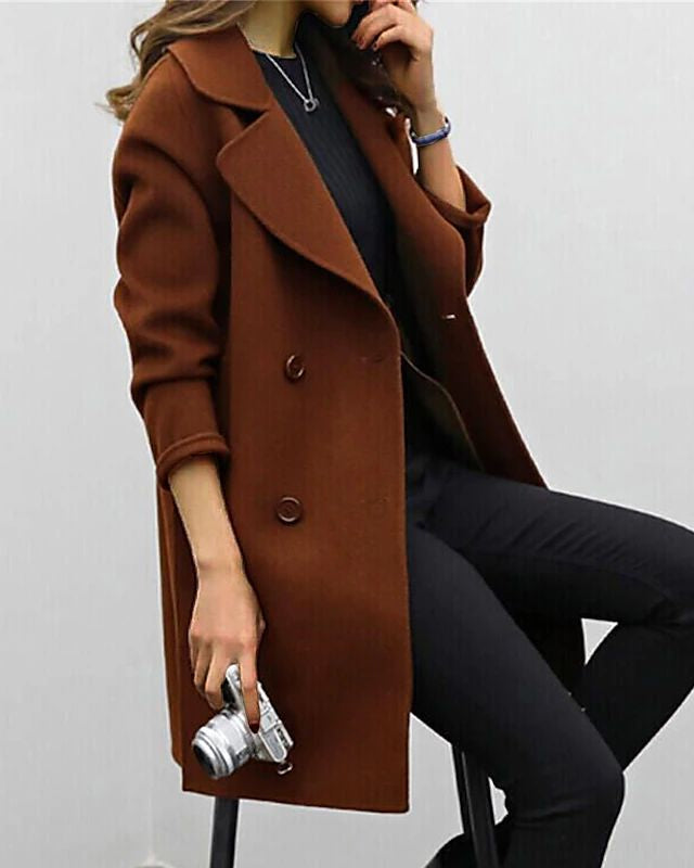 Donna con cappotto marrone elegante, seduta, tiene una fotocamera vintage. Moda autunnale, stile casual chic, abbigliamento femminile trendy.