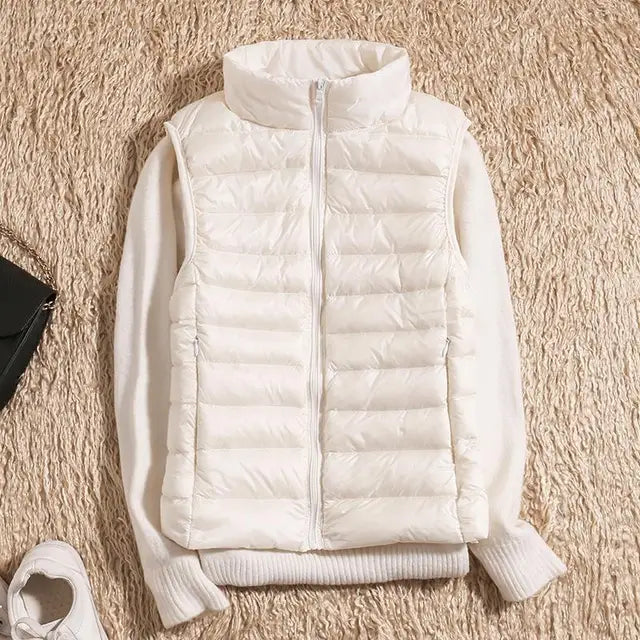 Gilet imbottito bianco su maglione beige, moda autunno inverno, abbigliamento casual donna, su sfondo di tappeto beige.