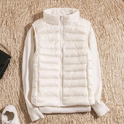 Gilet imbottito bianco su maglione beige, moda autunno inverno, abbigliamento casual donna, su sfondo di tappeto beige.