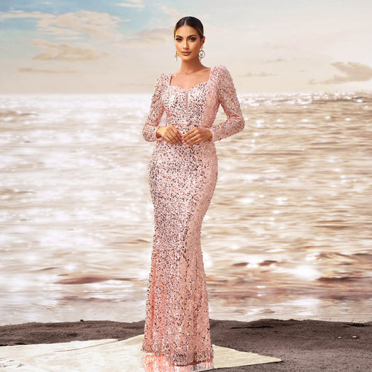 Donna in abito da sera rosa scintillante su spiaggia al tramonto, moda elegante, abito lungo con paillettes, sfondo mare e cielo nuvoloso.