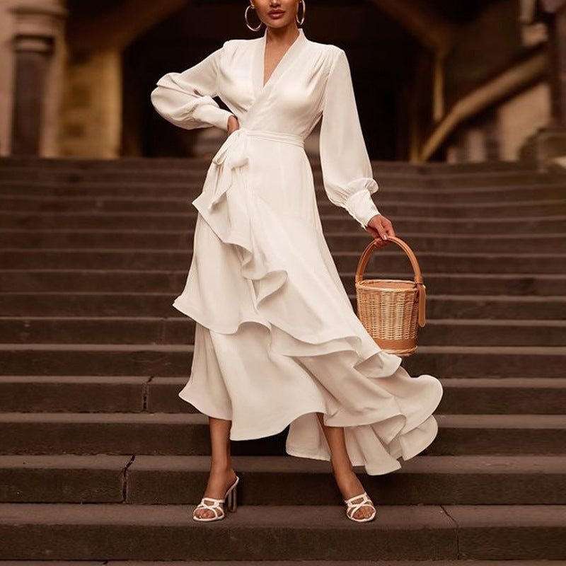 Donna in abito bianco elegante con volant, sandali bianchi e borsa di paglia su gradini. Moda femminile, stile estivo, abbigliamento chic.