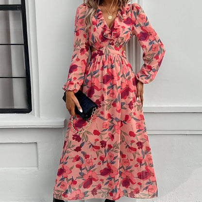 Abito lungo floreale rosa con maniche lunghe e scollo a V, indossato da una donna con borsa nera a catena dorata. Moda elegante e femminile.