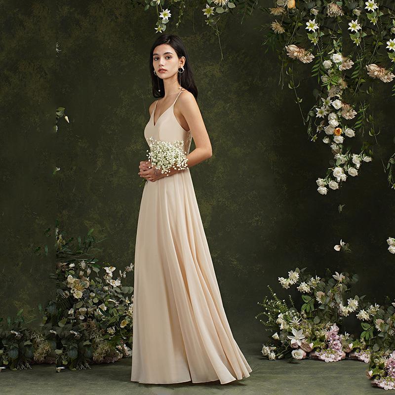 Donna in abito da sera beige, con bouquet di fiori bianchi, su sfondo floreale verde. Eleganza, moda femminile, abito lungo cerimonia.