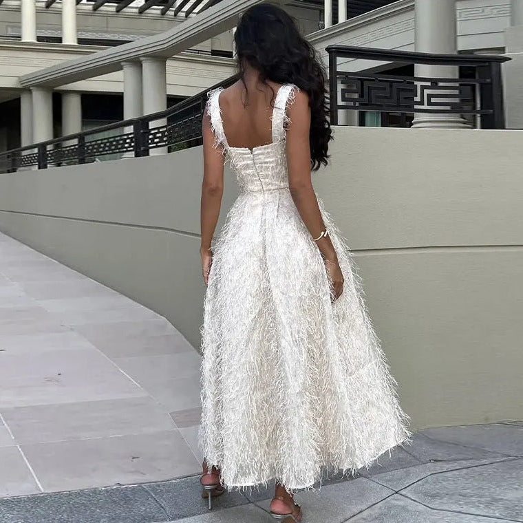 Donna in abito lungo bianco con frange, vista di spalle, su passerella moderna. Moda elegante, abbigliamento da sera, stile sofisticato.