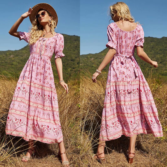 Donna in abito lungo floreale rosa, cappello di paglia, in un campo estivo. Moda estiva, abbigliamento boho chic, stile casual elegante.