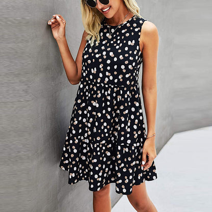 Abito estivo nero a pois bianchi, senza maniche, indossato da una donna sorridente con occhiali da sole. Moda casual femminile elegante.
