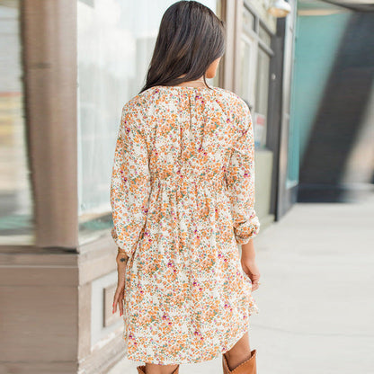 Donna di spalle con abito floreale estivo, maniche lunghe, in strada urbana. Moda femminile, abbigliamento casual, tendenze primavera estate.