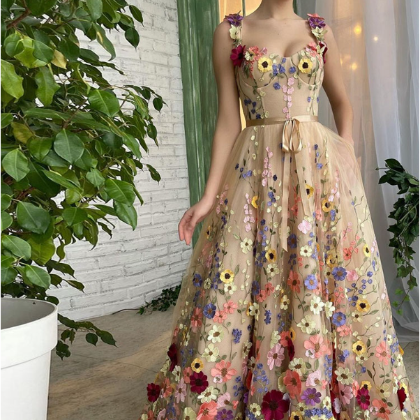 Abito lungo elegante con fiori colorati ricamati, sfondo bianco e verde, pianta in vaso. Perfetto per eventi speciali e cerimonie.