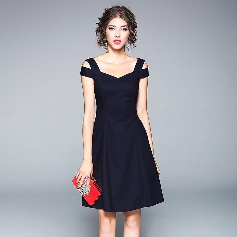 Donna in abito nero elegante con scollo a cuore, tiene una pochette rossa decorata. Moda femminile, abbigliamento da sera, accessori chic.