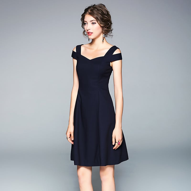 Donna in abito nero elegante, spalline incrociate, sfondo grigio. Moda femminile, abbigliamento da sera, stile sofisticato.