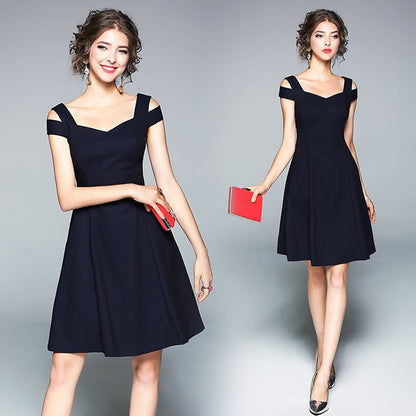 Donna in abito nero elegante con spalline, posa con libro rosso. Moda femminile, abbigliamento da sera, stile sofisticato. Sfondo grigio.