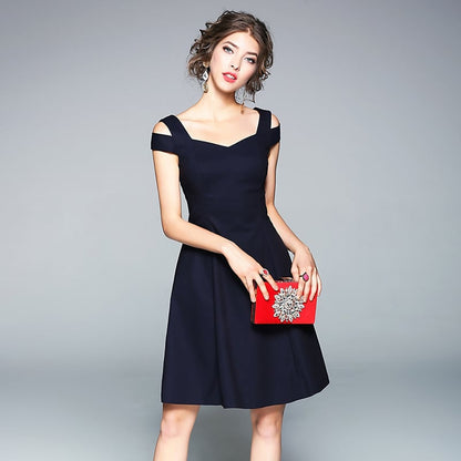 Donna in abito nero elegante con borsa rossa decorata, posa su sfondo grigio. Moda femminile, abbigliamento da sera, accessori di lusso.