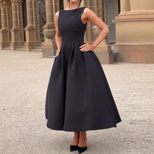Abito da sera nero elegante, senza maniche, con gonna ampia, indossato da una donna davanti a un edificio storico. Moda femminile classica.