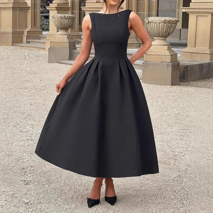Donna in elegante abito nero da sera, senza maniche, con gonna ampia, davanti a un edificio storico. Scarpe nere abbinate. Moda femminile classica.