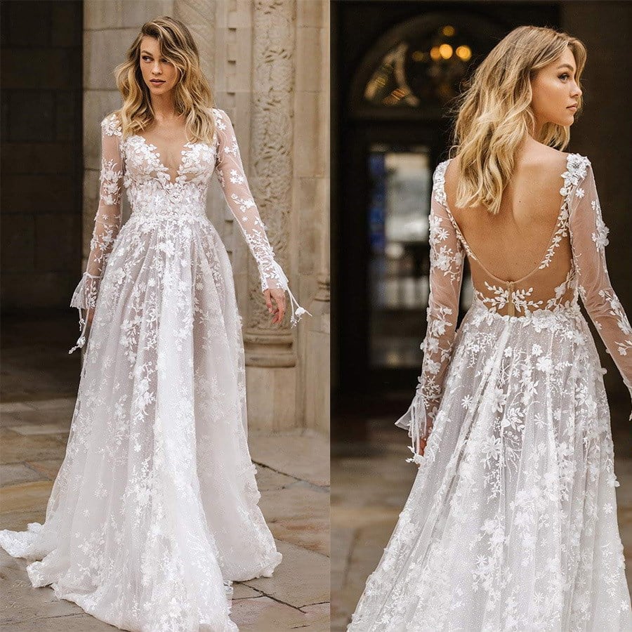 Abito da sposa in pizzo bianco con maniche lunghe trasparenti e scollo profondo, decorato con motivi floreali, elegante e moderno.