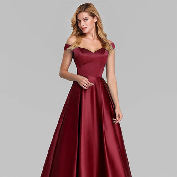 Donna in abito da sera rosso bordeaux, spalle scoperte, elegante e lungo. Moda femminile, abbigliamento formale, tendenza 2023.