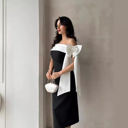 Donna in abito elegante nero e bianco con fiocco, borsa a mano bianca. Moda femminile, abbigliamento da sera, stile sofisticato.