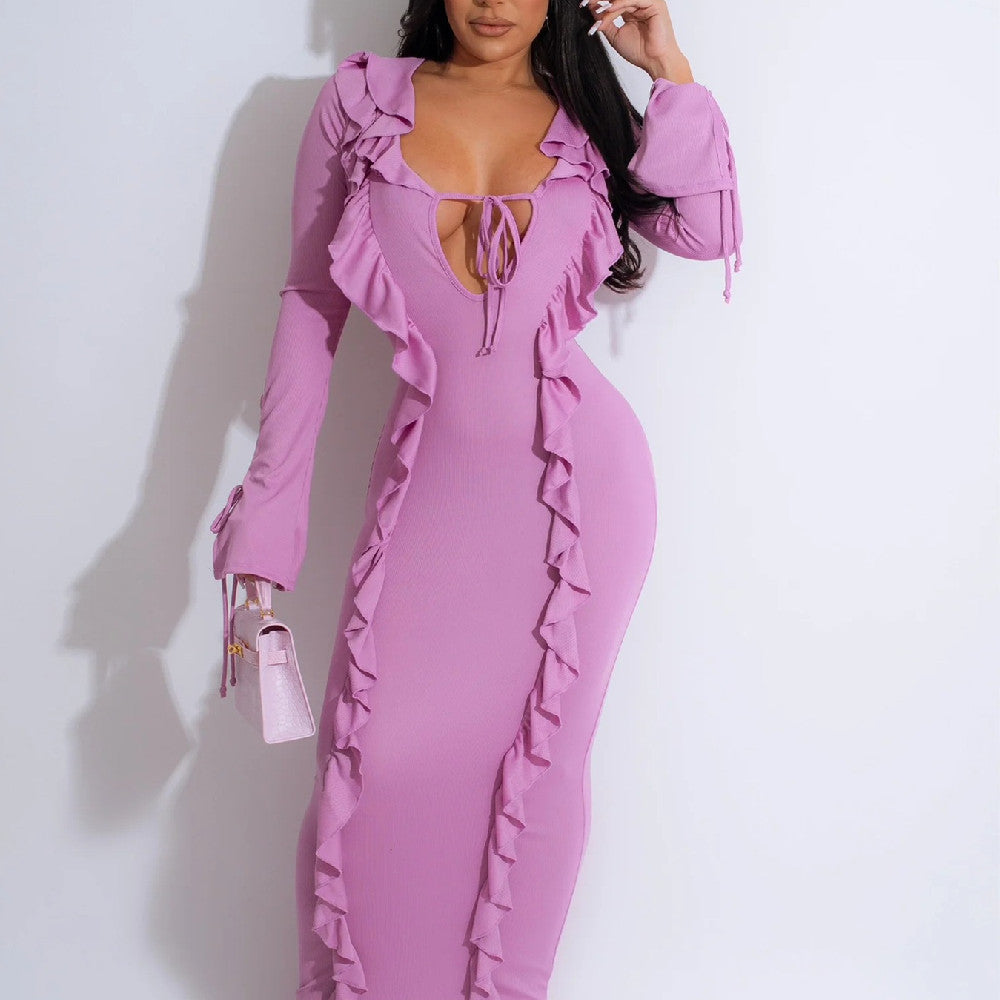 Donna in abito lungo rosa con volant, scollo profondo e maniche lunghe. Moda elegante, abbigliamento femminile, stile sofisticato.