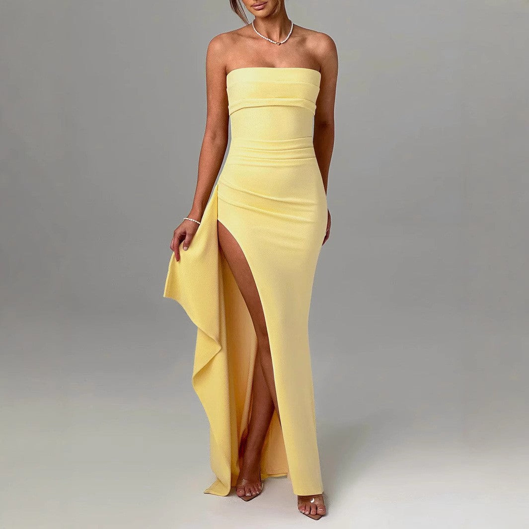 Abito lungo giallo elegante con spacco alto, senza spalline, indossato da una donna. Perfetto per eventi formali e serate glamour.