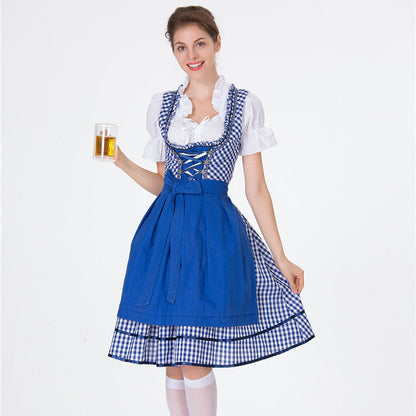 Donna in abito tradizionale bavarese blu con camicetta bianca, tiene un bicchiere di birra. Costume Oktoberfest, moda tedesca, festa della birra.