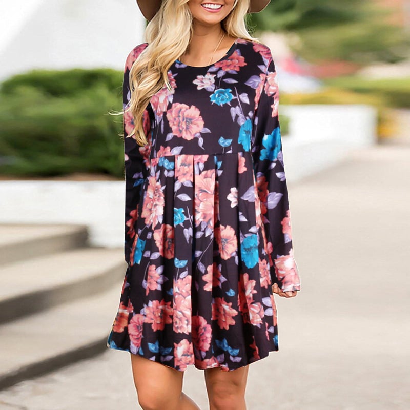 Donna con abito floreale colorato, maniche lunghe, sfondo urbano sfocato. Moda femminile, abbigliamento casual elegante, tendenze autunnali.