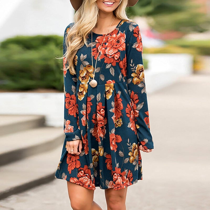Donna con abito floreale blu e rosso, cappello marrone, collana lunga; moda autunnale casual, stile elegante, tendenze abbigliamento femminile.