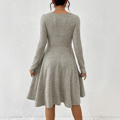 Donna in abito grigio a coste, maniche lunghe, scollo rotondo, lunghezza al ginocchio, sfondo bianco. Moda autunnale elegante e casual.