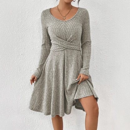 Abito grigio a coste con maniche lunghe e scollo a V, design incrociato in vita, tessuto morbido e fluente, perfetto per look casual ed eleganti.