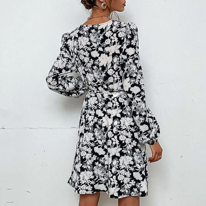 Donna con abito floreale bianco e nero, maniche lunghe, sfondo bianco. Moda femminile elegante, abbigliamento casual chic.