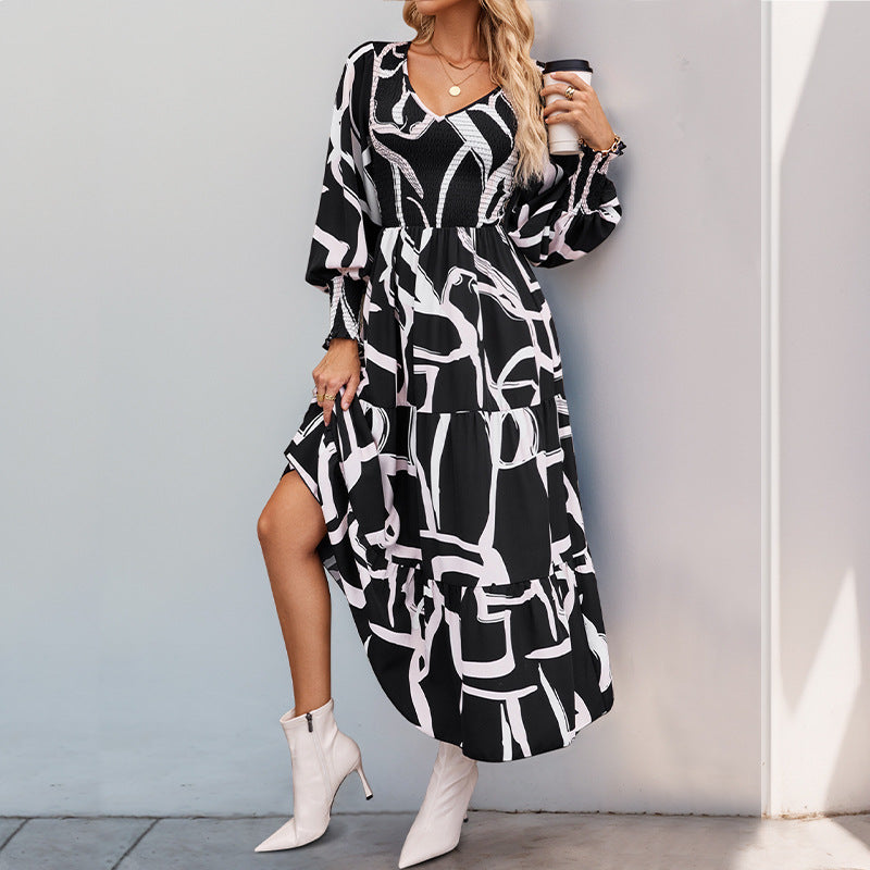 Donna con abito lungo a fantasia geometrica bianco e nero, stivali bianchi, posa elegante. Moda autunnale, stile chic, abbigliamento femminile trendy.
