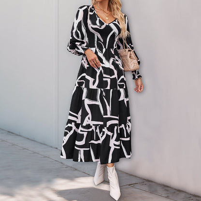 Donna con abito lungo a fantasia bianco e nero, borsa beige e stivali bianchi. Moda autunnale elegante, look casual chic per strada.