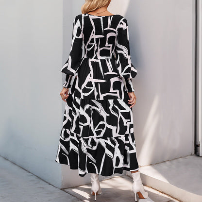 Donna con abito lungo nero e bianco a motivi geometrici, maniche lunghe, in piedi su marciapiede. Moda femminile elegante, stile moderno.
