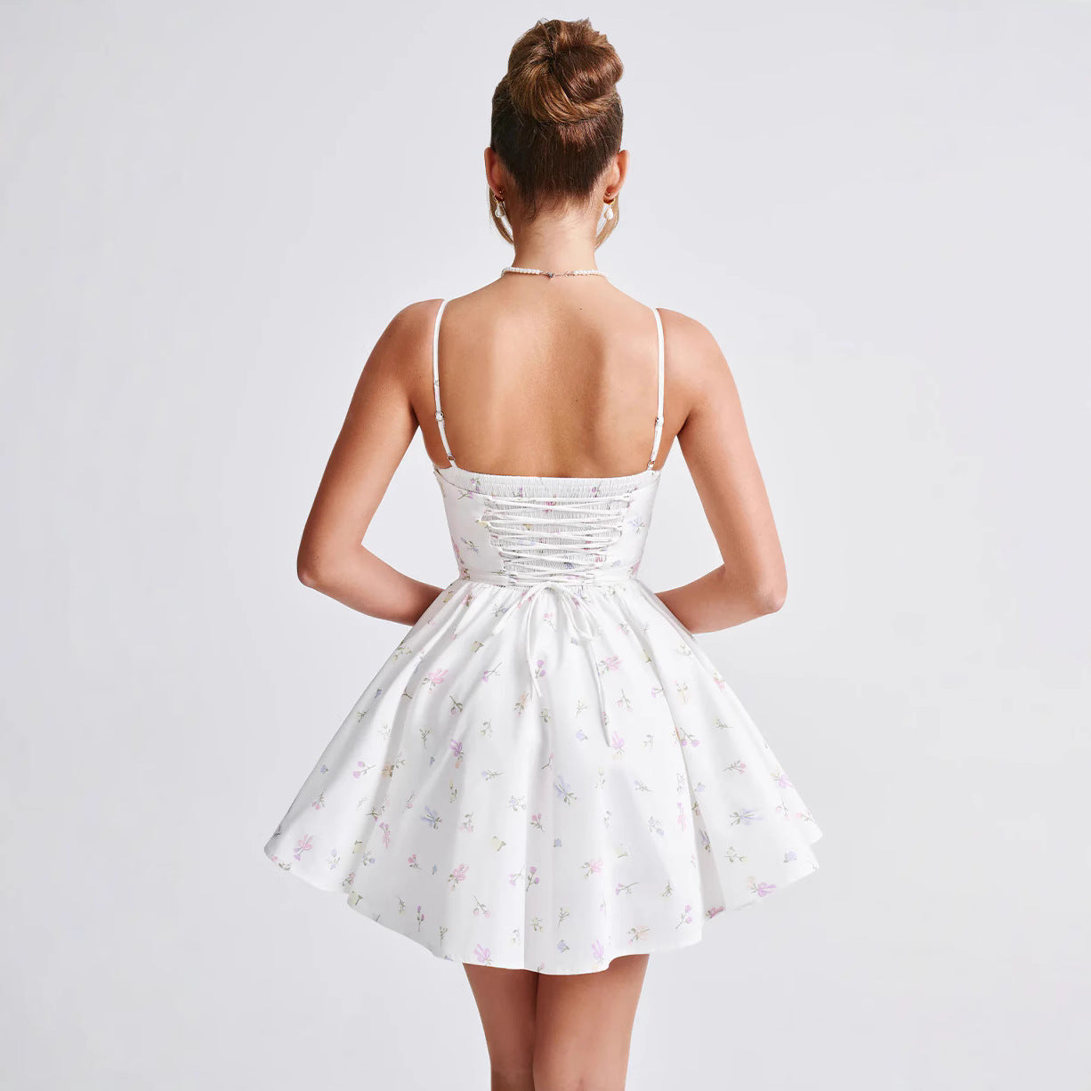 Donna in abito estivo bianco con spalline sottili e stampa floreale, vista posteriore. Moda femminile, abbigliamento estivo elegante.