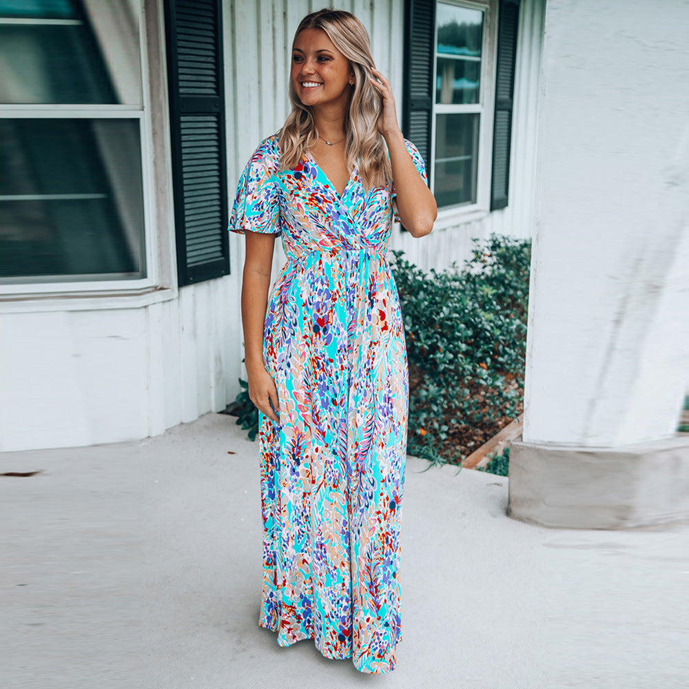 Donna sorridente in abito lungo estivo colorato davanti a casa bianca con finestre e persiane nere. Moda femminile, abbigliamento estivo elegante.