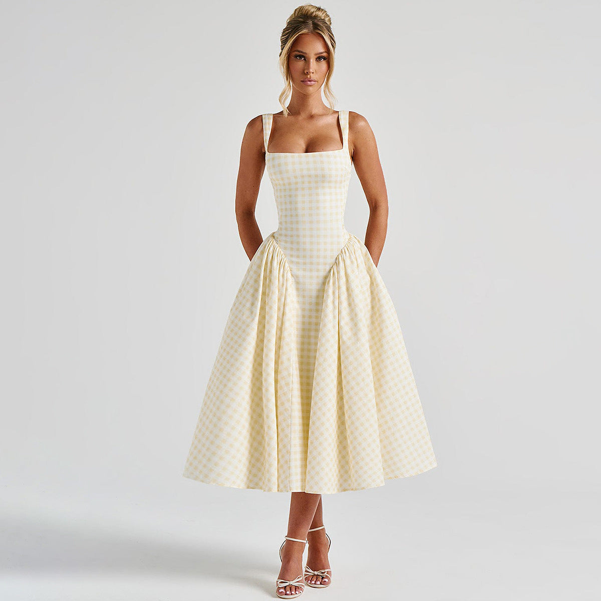 Donna in abito a quadri gialli e bianchi, stile vintage anni '50, con spalline sottili e gonna ampia. Eleganza retrò, moda femminile, abbigliamento estivo.
