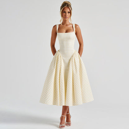 Donna in abito a quadri gialli e bianchi, stile vintage anni '50, con spalline sottili e gonna ampia. Eleganza retrò, moda femminile, abbigliamento estivo.
