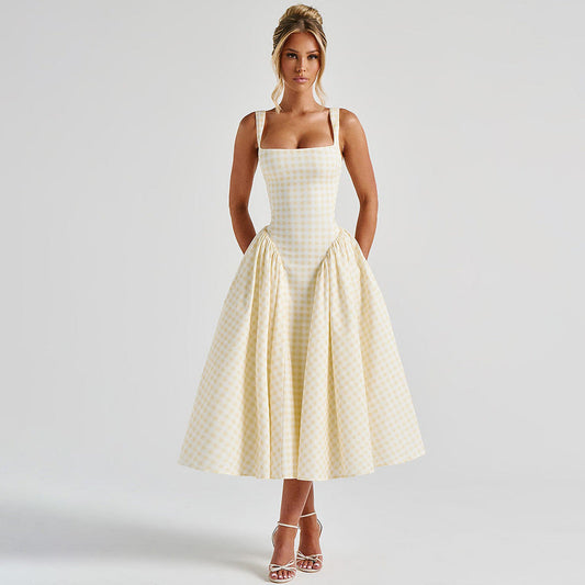 Donna in abito a quadri gialli e bianchi, stile vintage anni '50, con spalline sottili e gonna ampia. Eleganza retrò, moda femminile, abbigliamento estivo.
