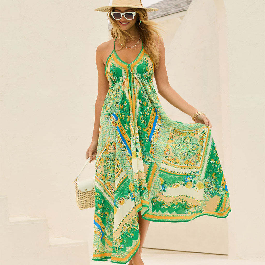 Donna con abito estivo lungo verde con motivi geometrici, cappello di paglia e occhiali da sole, posa sorridente all'aperto.