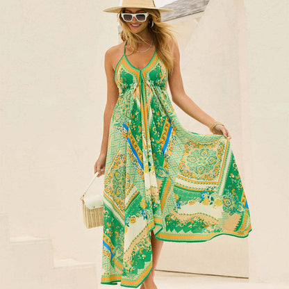 Donna con abito estivo lungo verde con motivi geometrici, cappello di paglia e occhiali da sole, posa sorridente all'aperto.