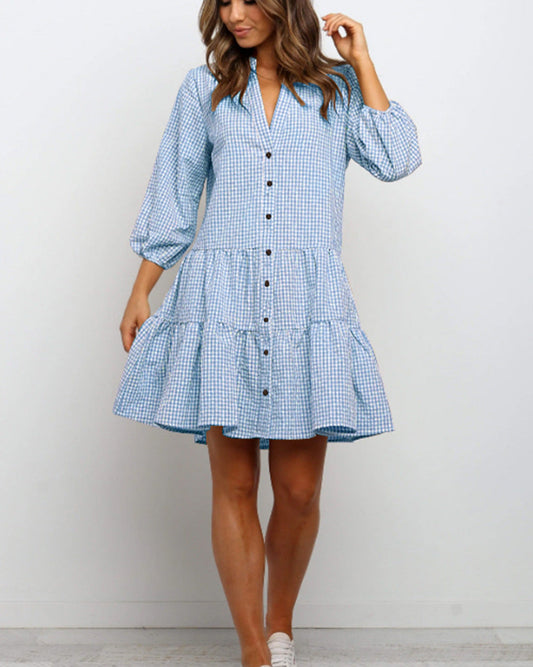 Donna con abito a quadri azzurri e bianchi, maniche a tre quarti, bottoni frontali, orlo a balze. Moda casual, stile estivo, abbigliamento femminile.