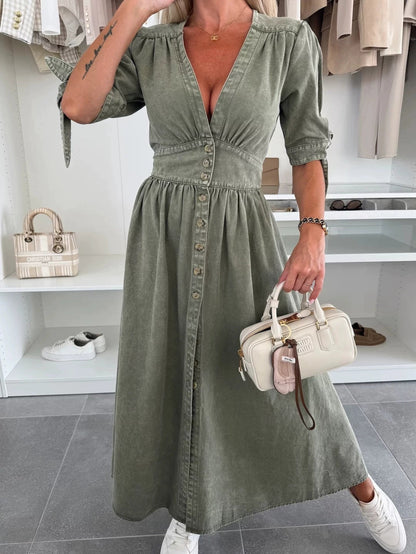 Donna in abito verde oliva con bottoni, borsa a mano bianca, scarpe da ginnastica bianche, in negozio di moda. Stile casual chic, moda femminile.