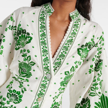 Camicia bianca con motivi floreali verdi, maniche ampie e dettagli in pizzo. Moda femminile elegante, stile boho-chic, abbigliamento estivo.