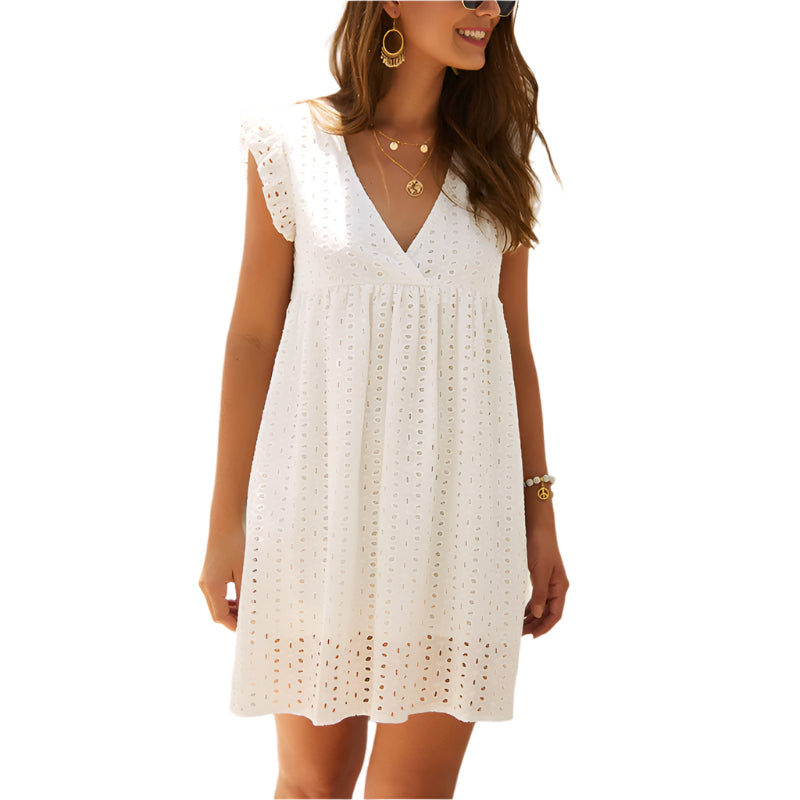 Donna con abito estivo bianco in pizzo traforato, scollo a V, maniche corte, accessori dorati. Moda estiva elegante e casual.
