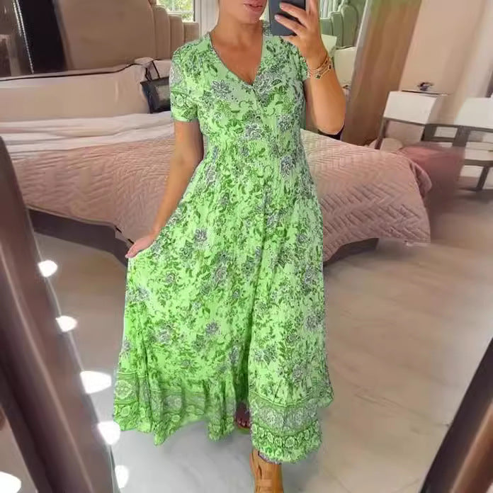 Donna in abito lungo verde floreale, scatta selfie in camera da letto moderna. Moda estiva, vestito casual elegante, tendenze abbigliamento femminile.