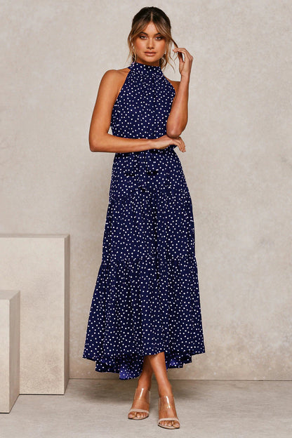 Donna in abito lungo blu a pois bianchi, senza maniche, con sandali trasparenti. Moda elegante, abbigliamento estivo, stile chic.
