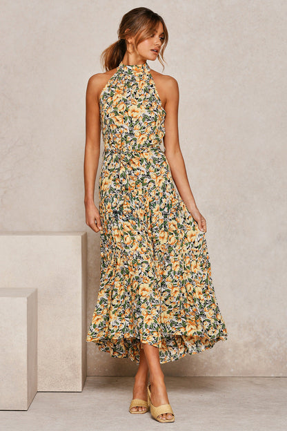Donna in abito lungo floreale giallo, senza maniche, con sandali beige. Moda estiva elegante, abbigliamento femminile, tendenze 2023.